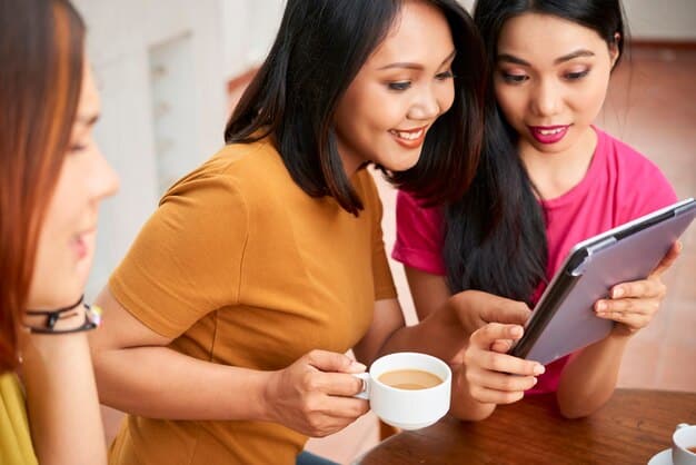 A diverse group of Filipino friends discussing their financial plans over coffee, using a tablet to visualize their budget. They are collaborating and sharing tips.