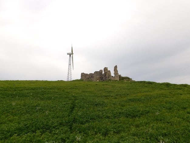 A scenic shot of a wind turbine farm located in a mountainous region in the Philippines. The turbines are tall and white, contrasting against the green hills and blue sky. The image conveys the scale and impact of wind energy in a rural setting.